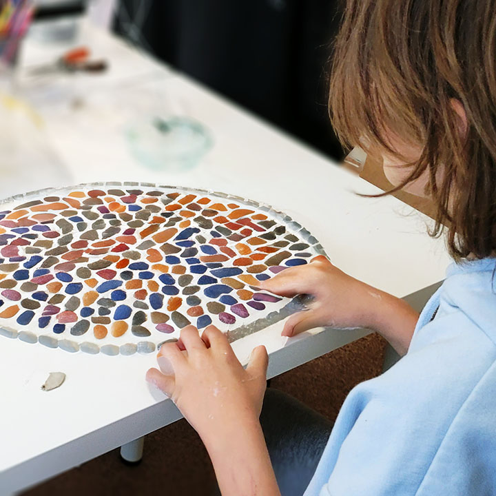 Chłopczyk układa mozaikę na wakacyjnych warsztatach 2024 w Katowicach